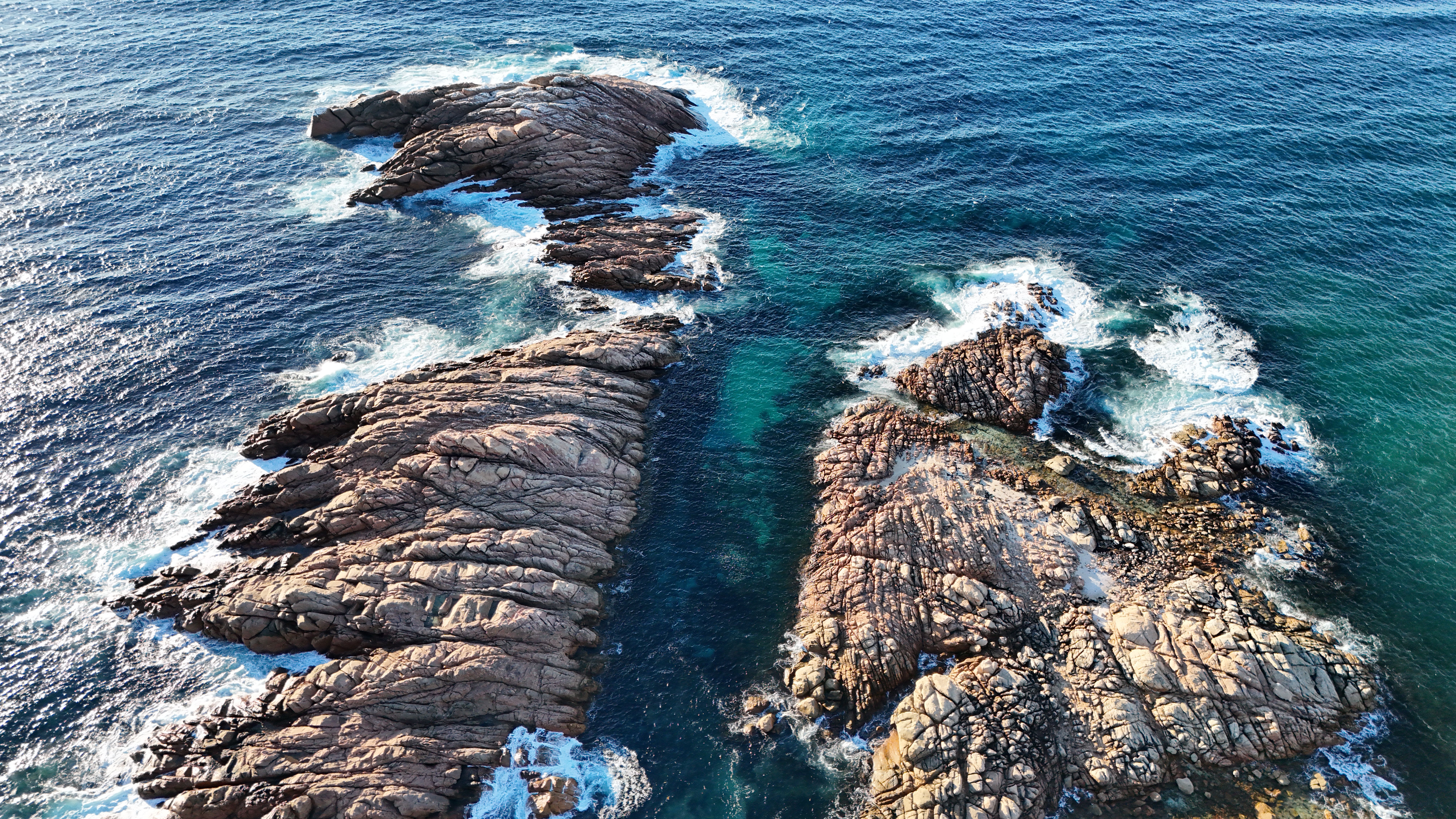25-Minute Uluru and Kata Tjuta Scenic Helicopter Flight - Stunning aerial shot of rocky formations on the coastline of Perth, Australia with vibrant blue ocean.