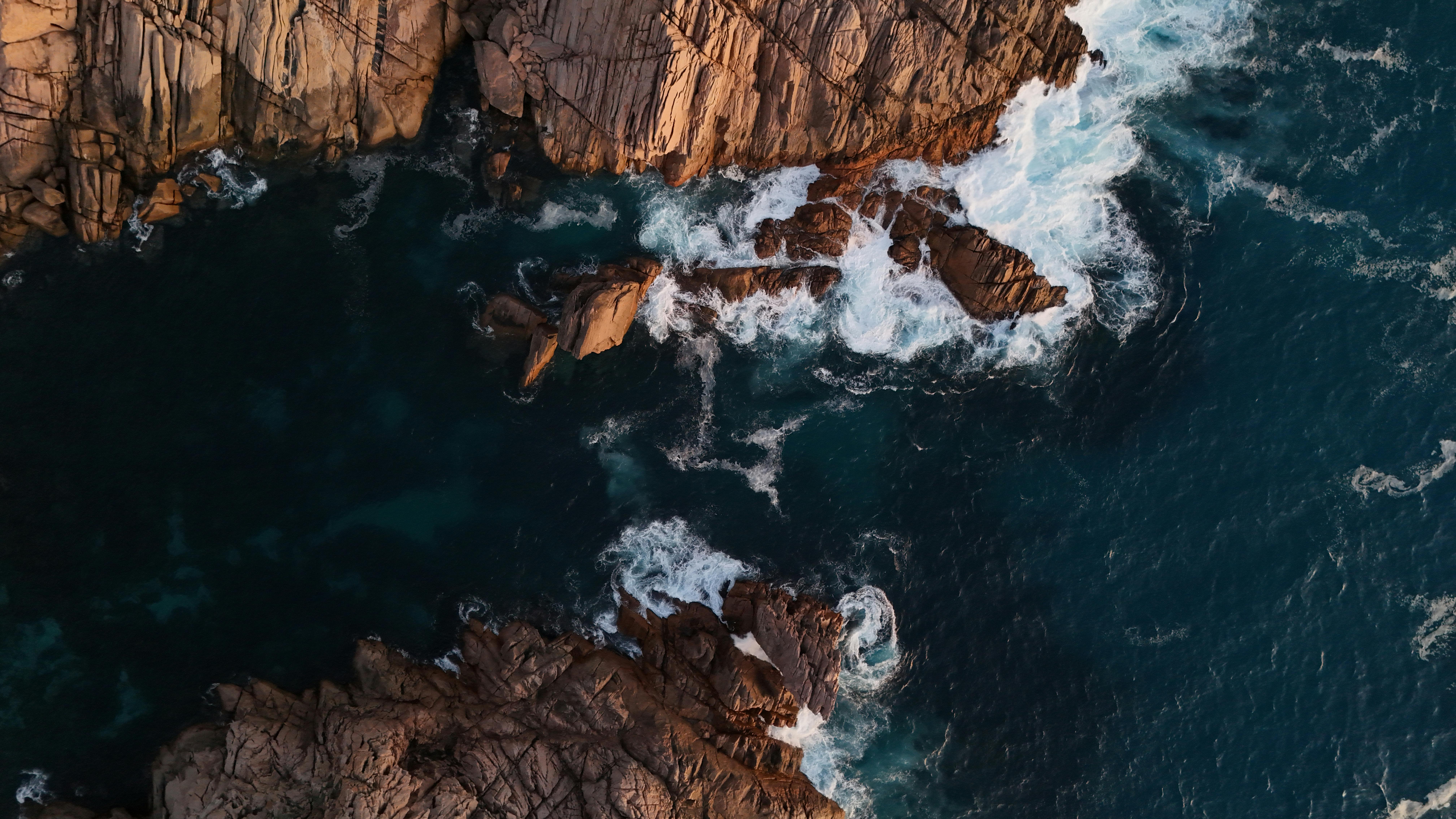 Explore the stunning rocky cliffs and ocean waves of Australia's coastline from above.