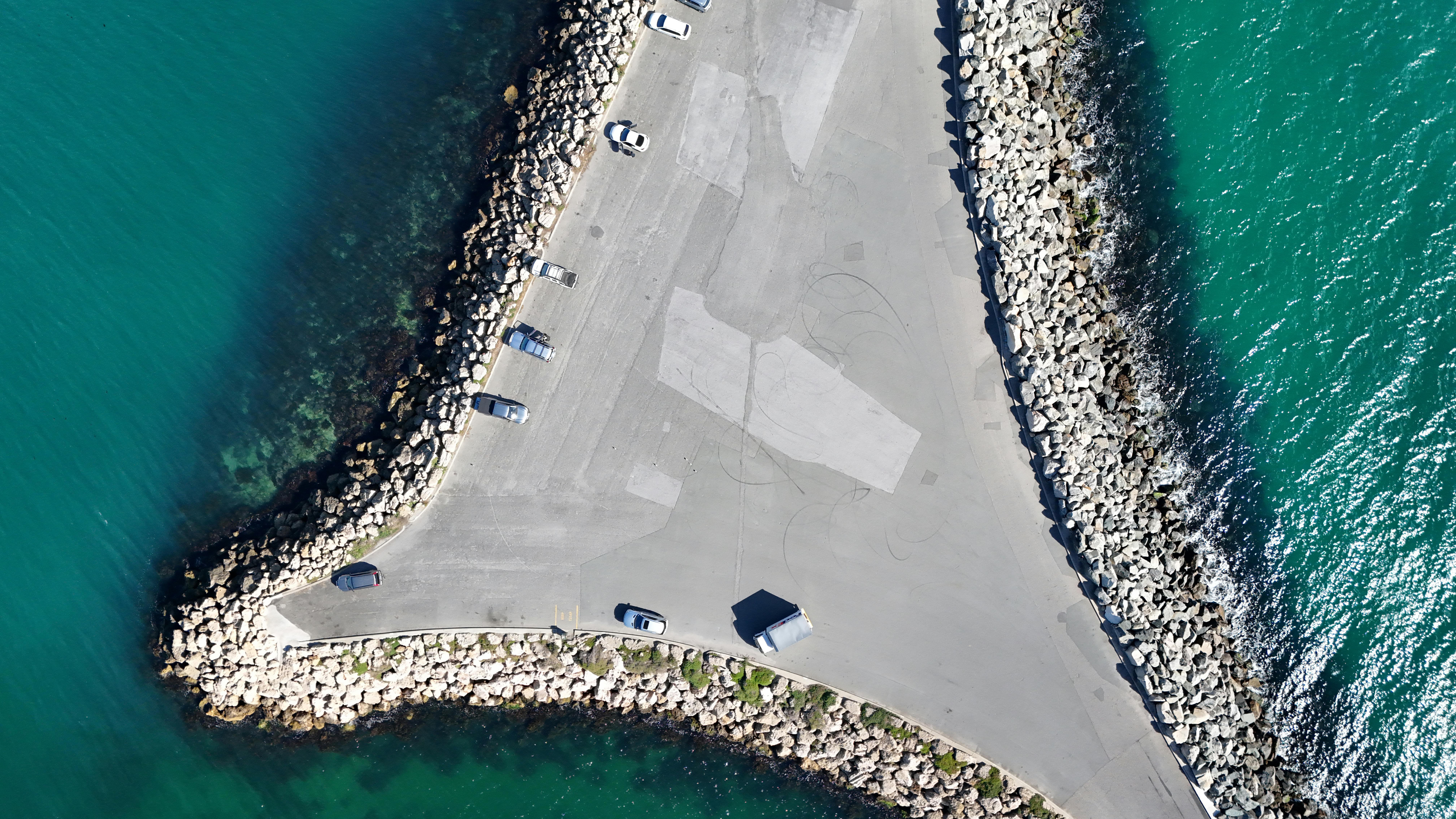 Drone shot of a coastal road with rock barriers in Perth, WA, Australia.