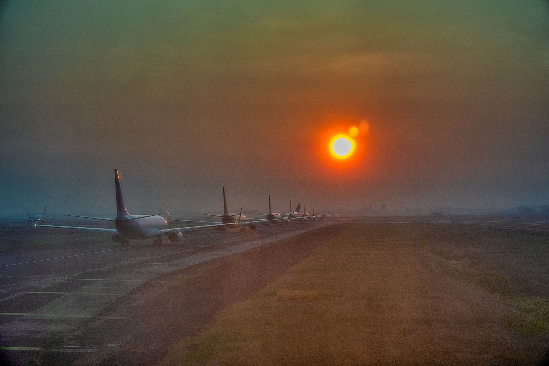 Un avión estacionado en la pista de un aeropuerto al atardecer