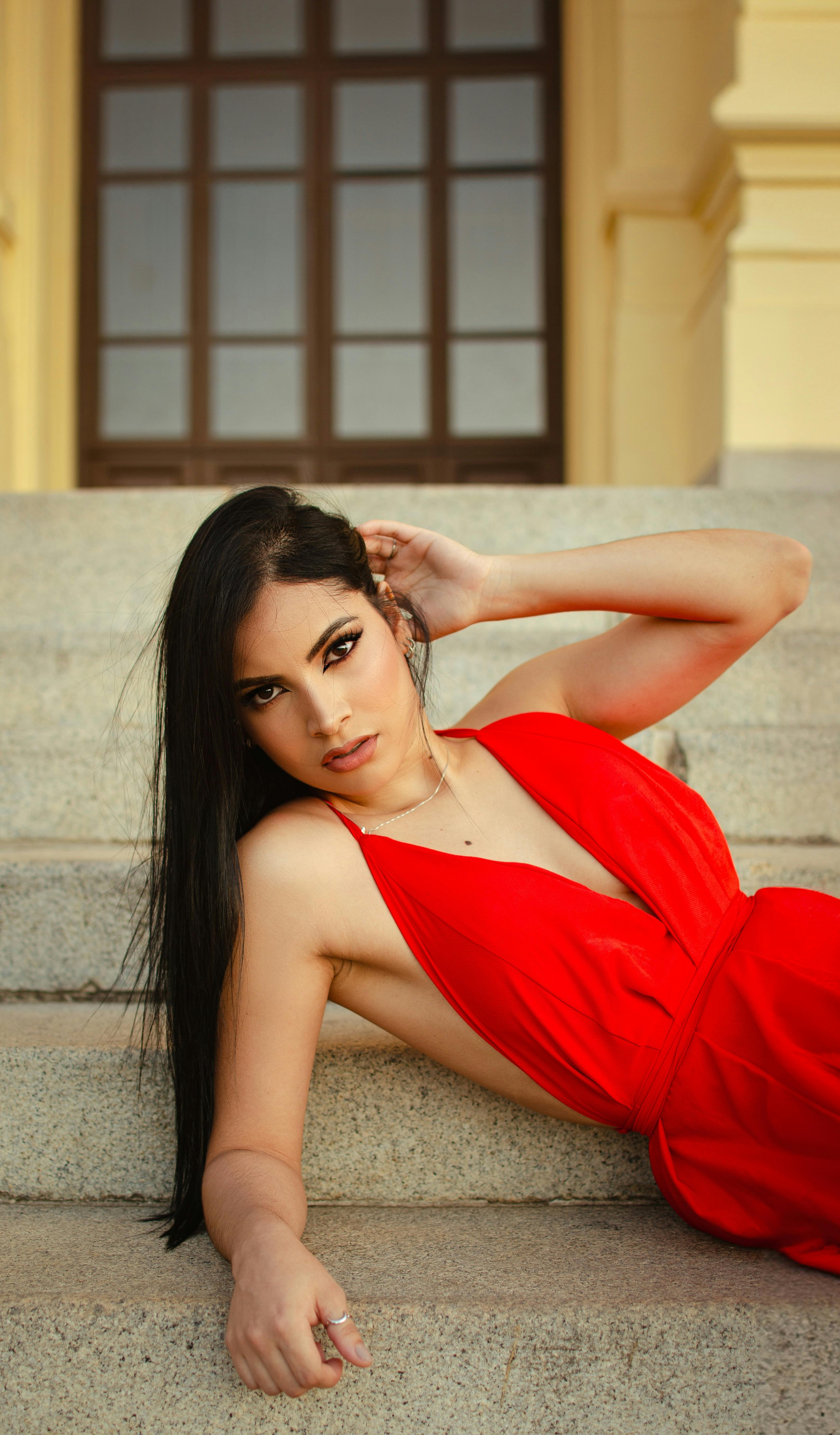 a woman in a red dress laying on some steps