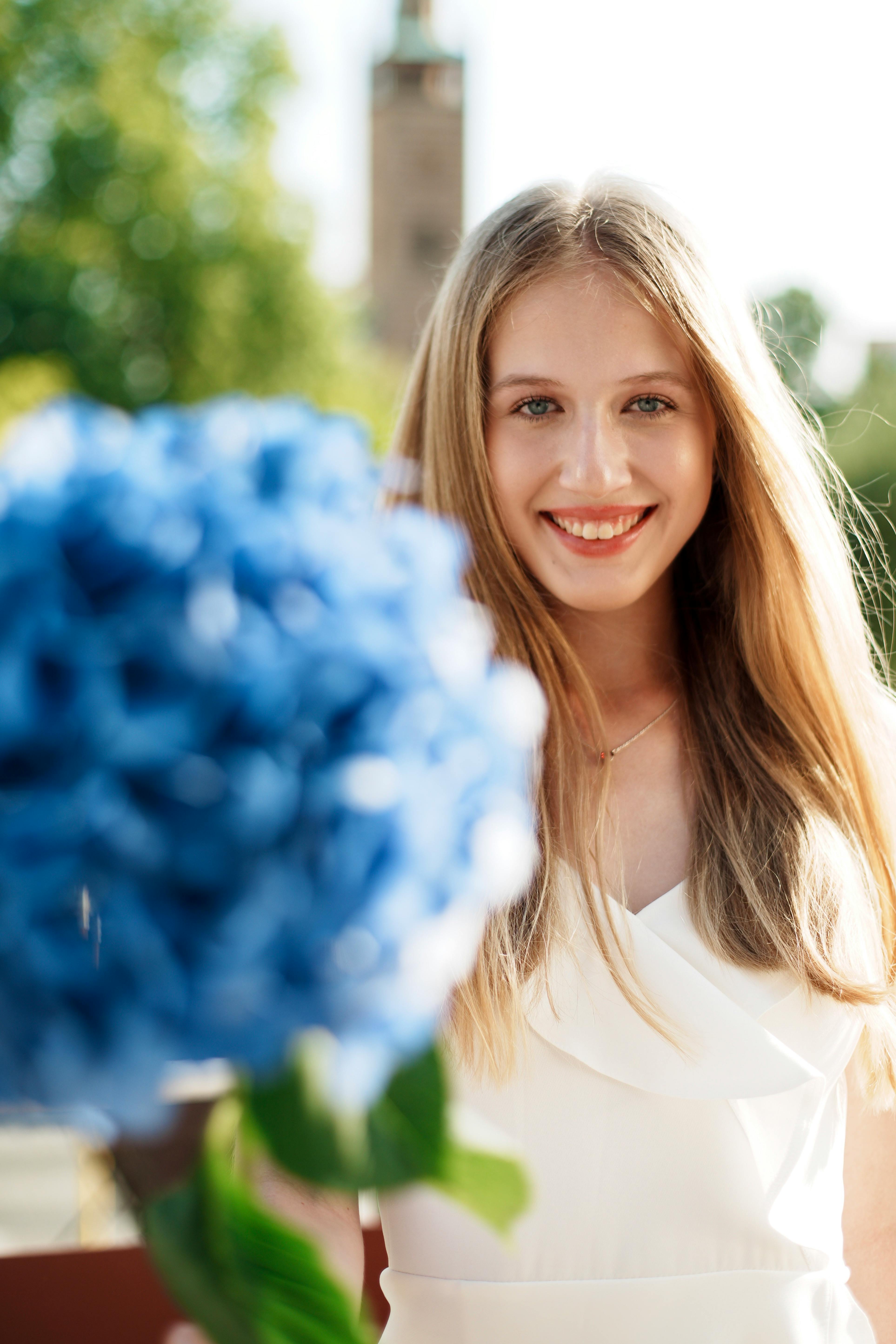 a beautiful blonde woman holding a bouquet of blue flowers