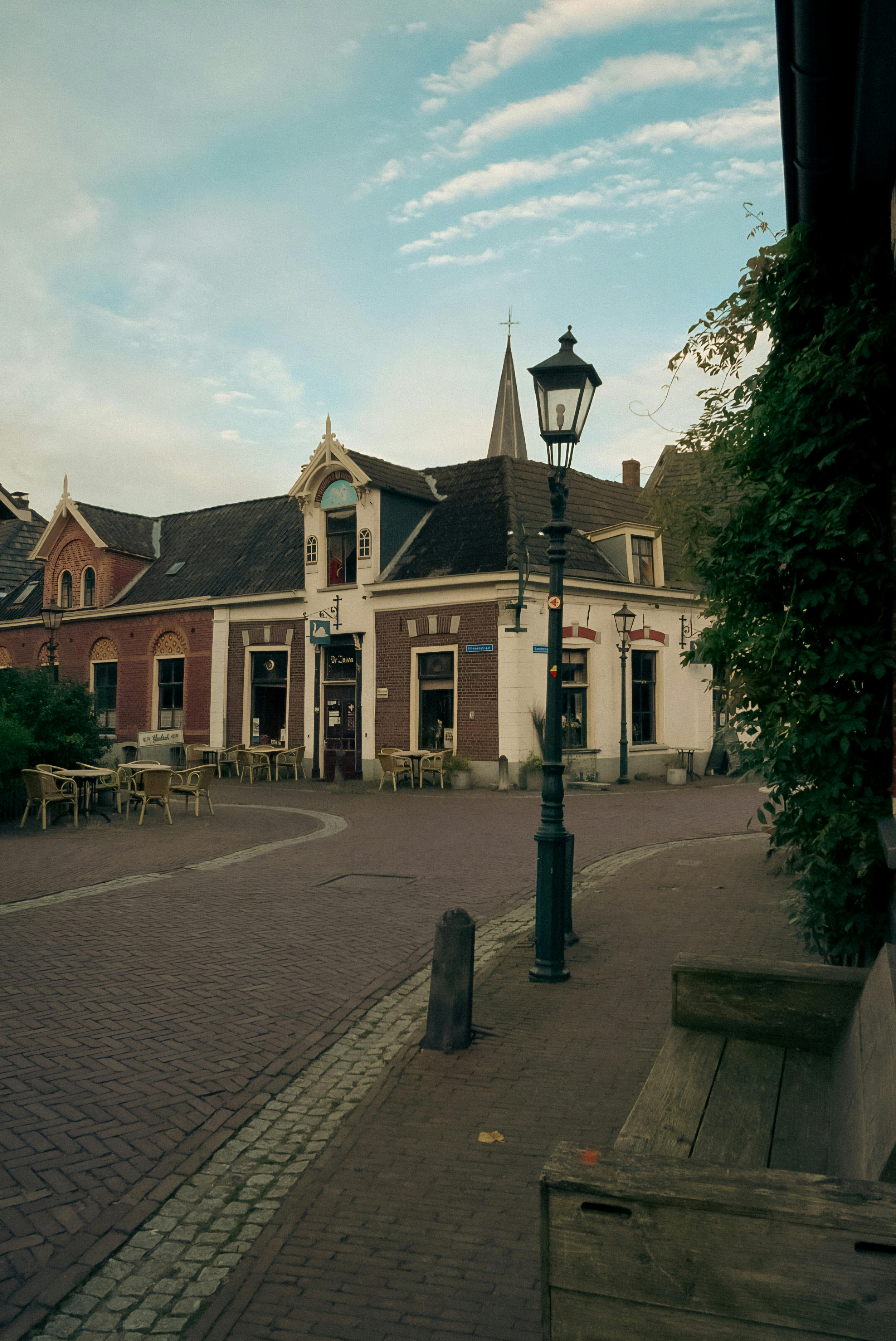 Cozy street corner in Europe showcasing vintage architecture with empty outdoor seating on a calm day.