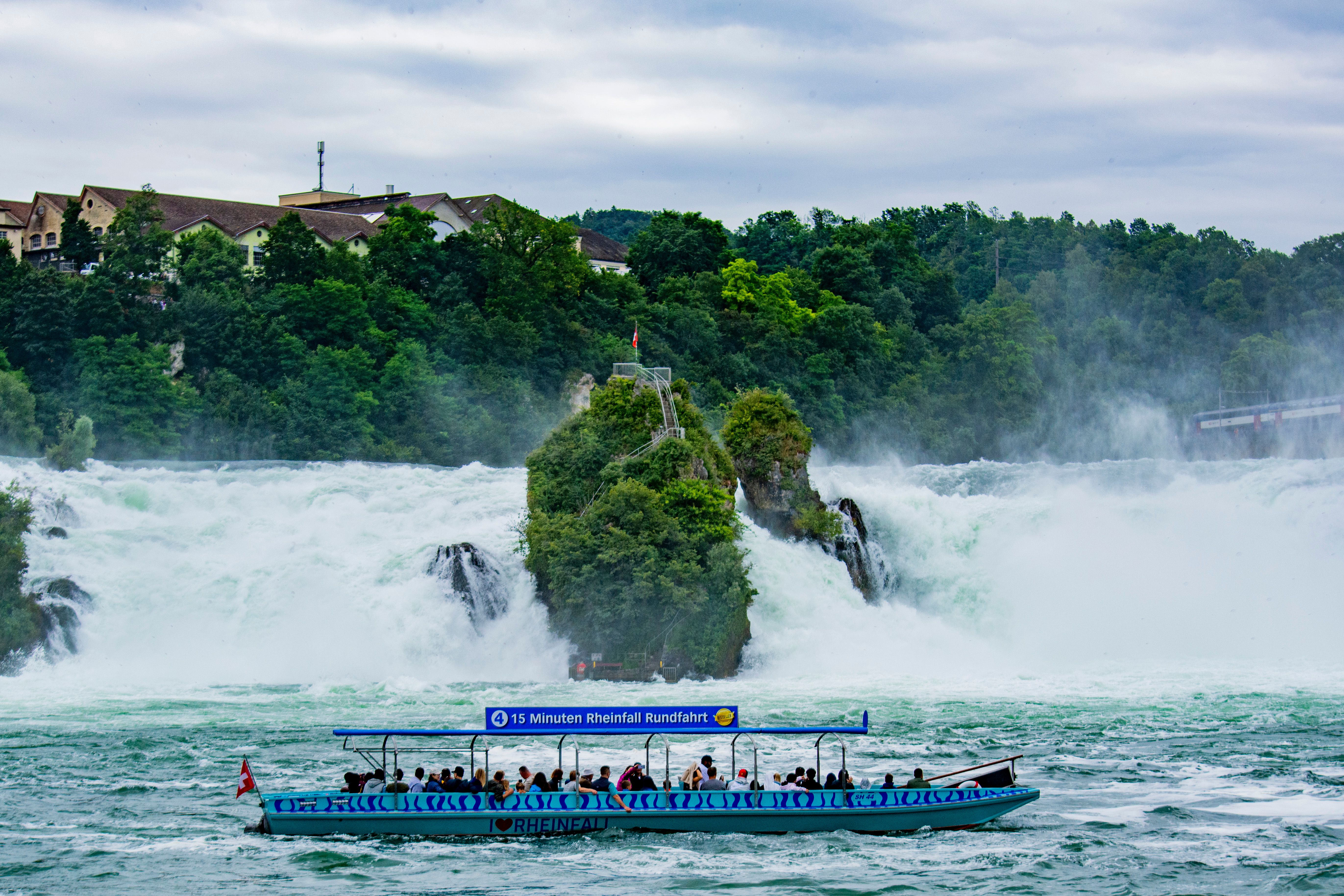 Tourists enjoy a scenic boat ride below Switzerland's stunning Rhine Falls. - Schaffhausen