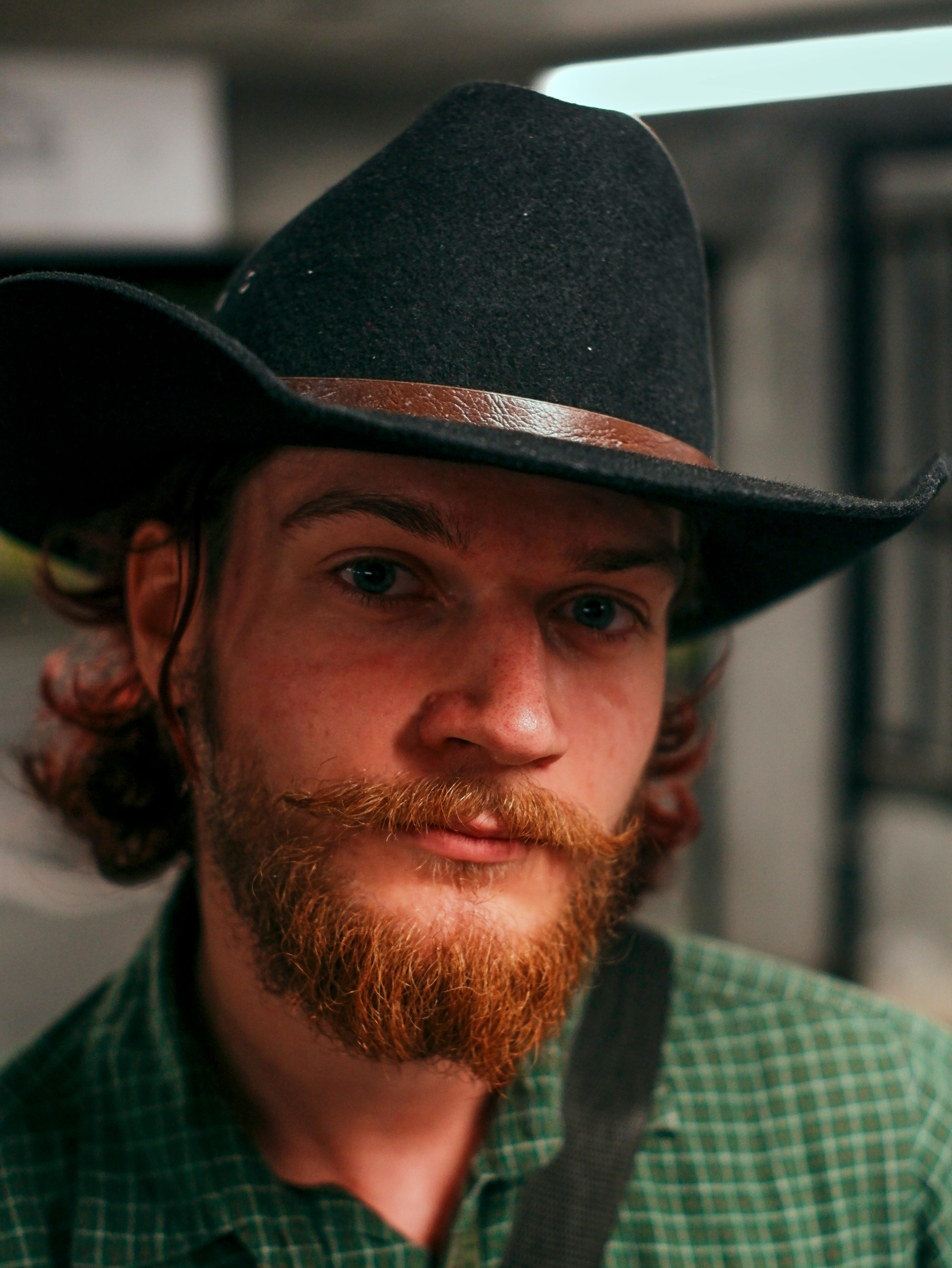 a man with a beard and long red hair wearing a cowboy hat