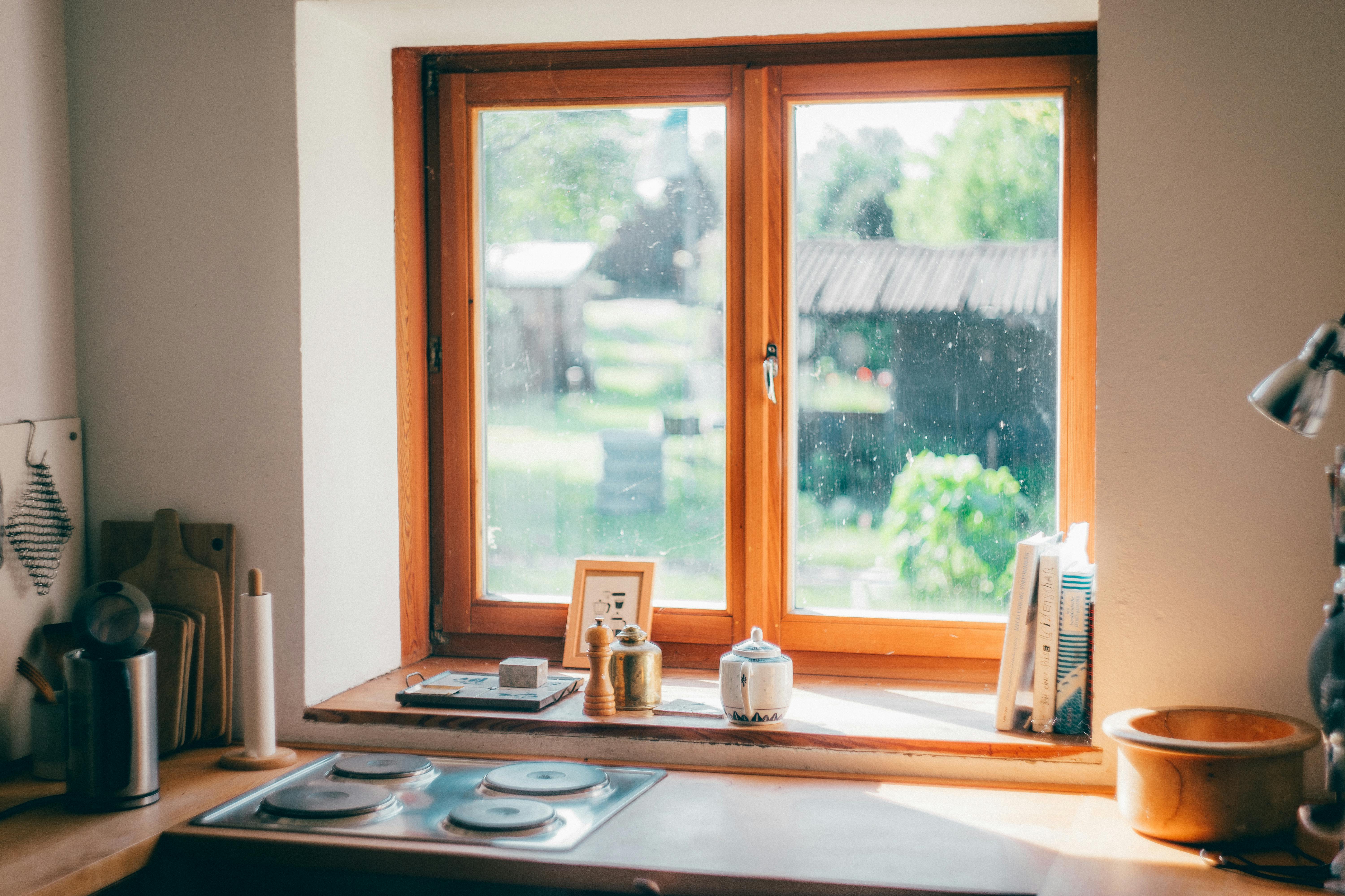 Sunlit kitchen window with view, capturing cozy interior and outdoor greenery.
