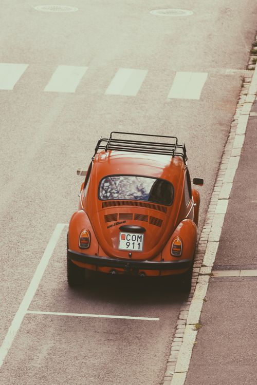 Free A classic red Volkswagen Beetle parked on an empty street in Jönköping, Sweden. Ideal for retro car enthusiasts. Stock Photo