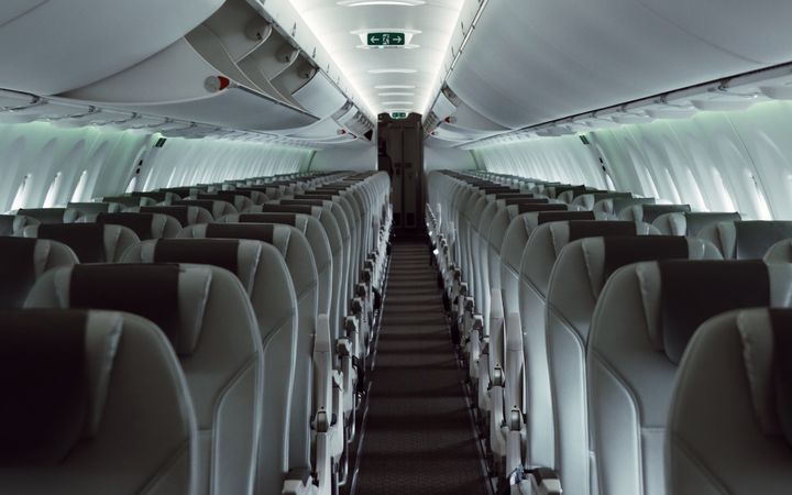 A sleek view of an empty airplane cabin showcasing modern interior design and lighting.