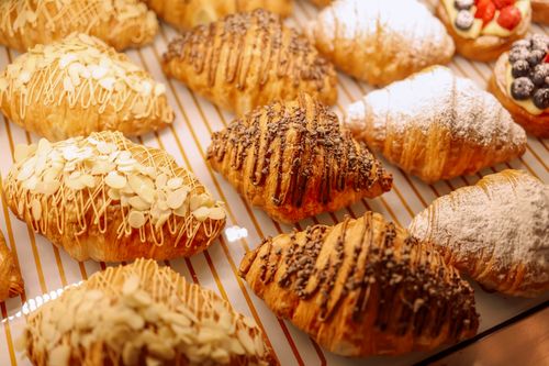 Free Assorted pastries topped with almonds, chocolate, and powdered sugar in a bakery display. Stock Photo