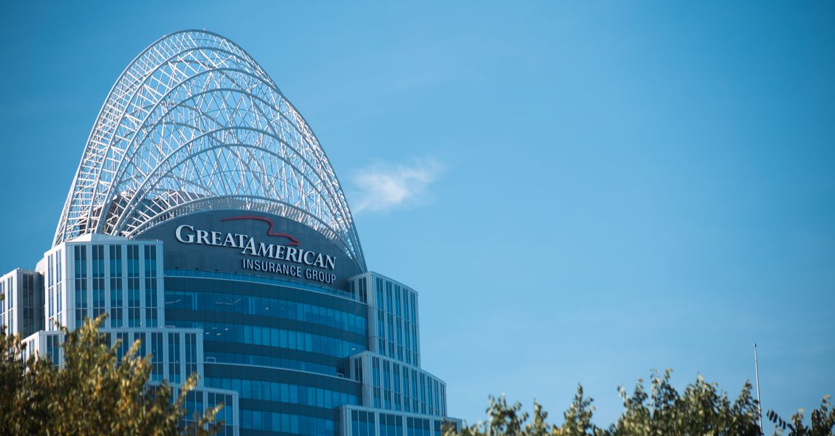 Modern skyscraper, Great American Tower, with arch top set against clear blue sky and foliage in Cincinnati.