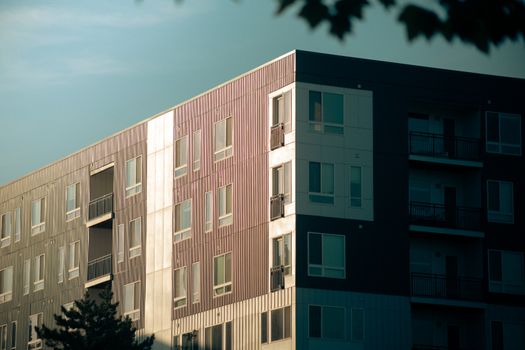 Contemporary urban apartment building with balconies and glass windows at sunset.