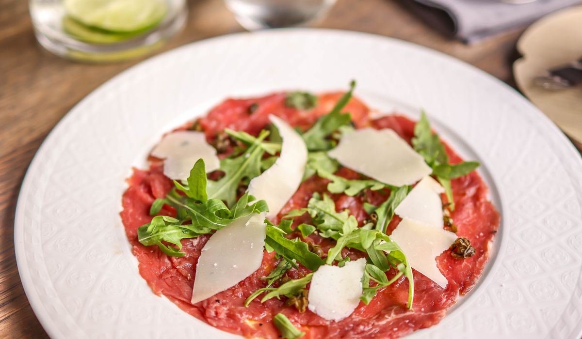 Plated dish of sliced meat with fresh vegetables showing classic carpaccio-style presentation