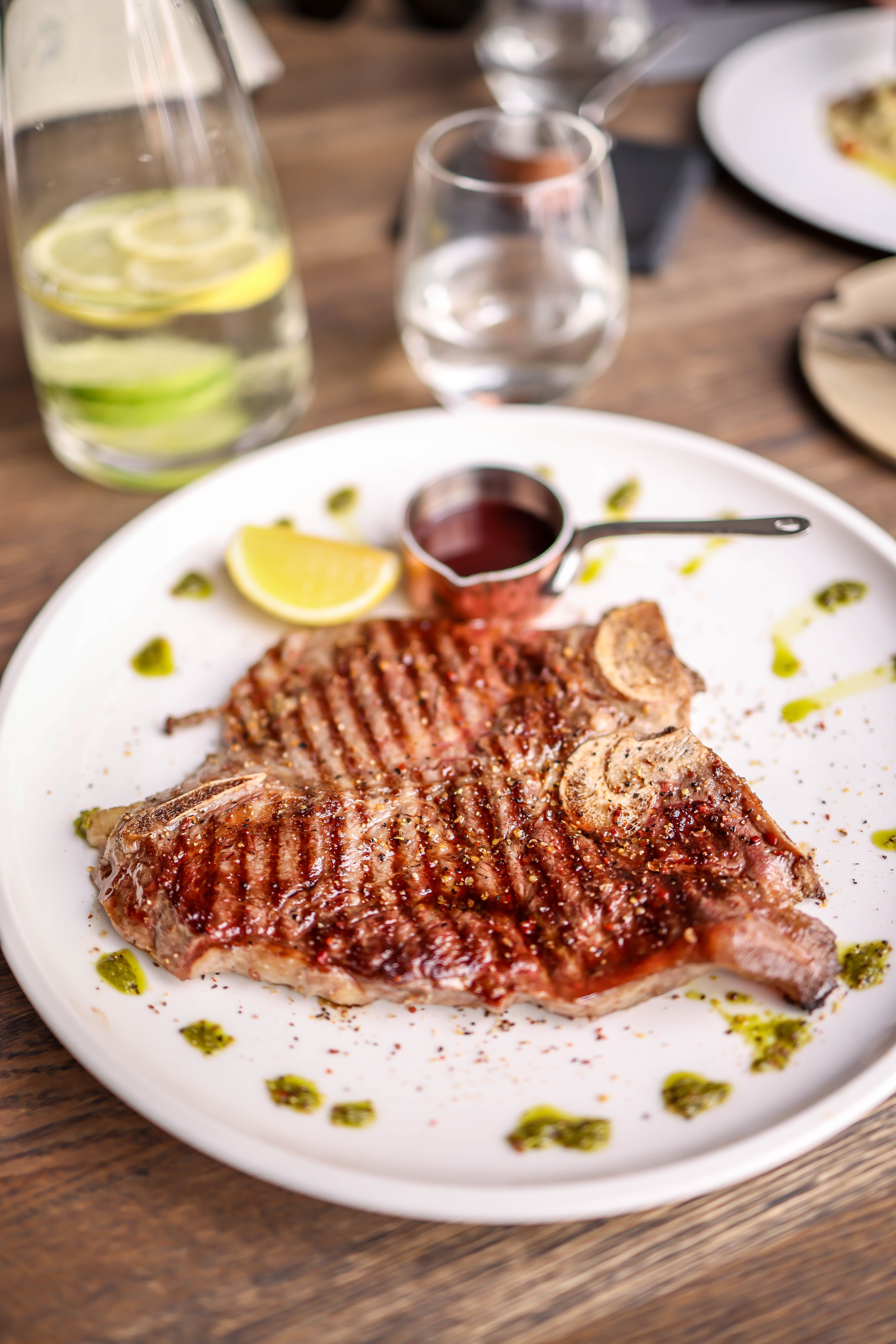 Juicy grilled steak with lemon and sauce on a white plate, perfect for dinner.