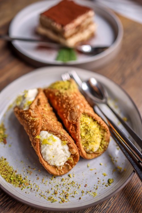 Free Appetizing cannoli and tiramisu on plates, perfect for dessert lovers. Stock Photo