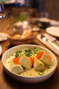 Delicious fish rolls garnished with caviar and herbs in a creamy sauce, perfect for fine dining.