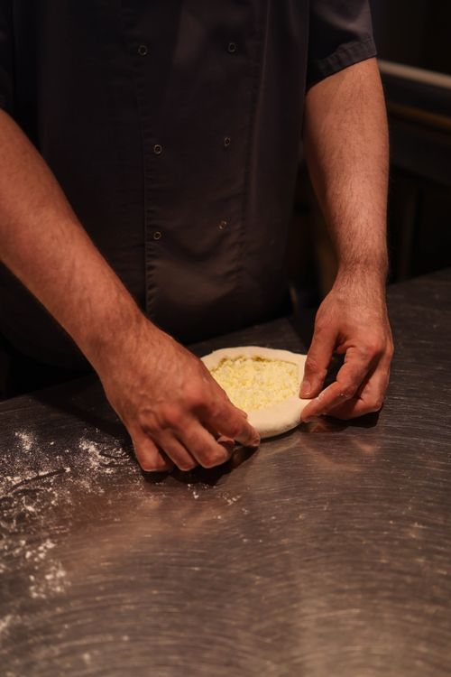 Free A chef's hands skillfully shape pizza dough on a flour-dusted stainless steel countertop. Stock Photo