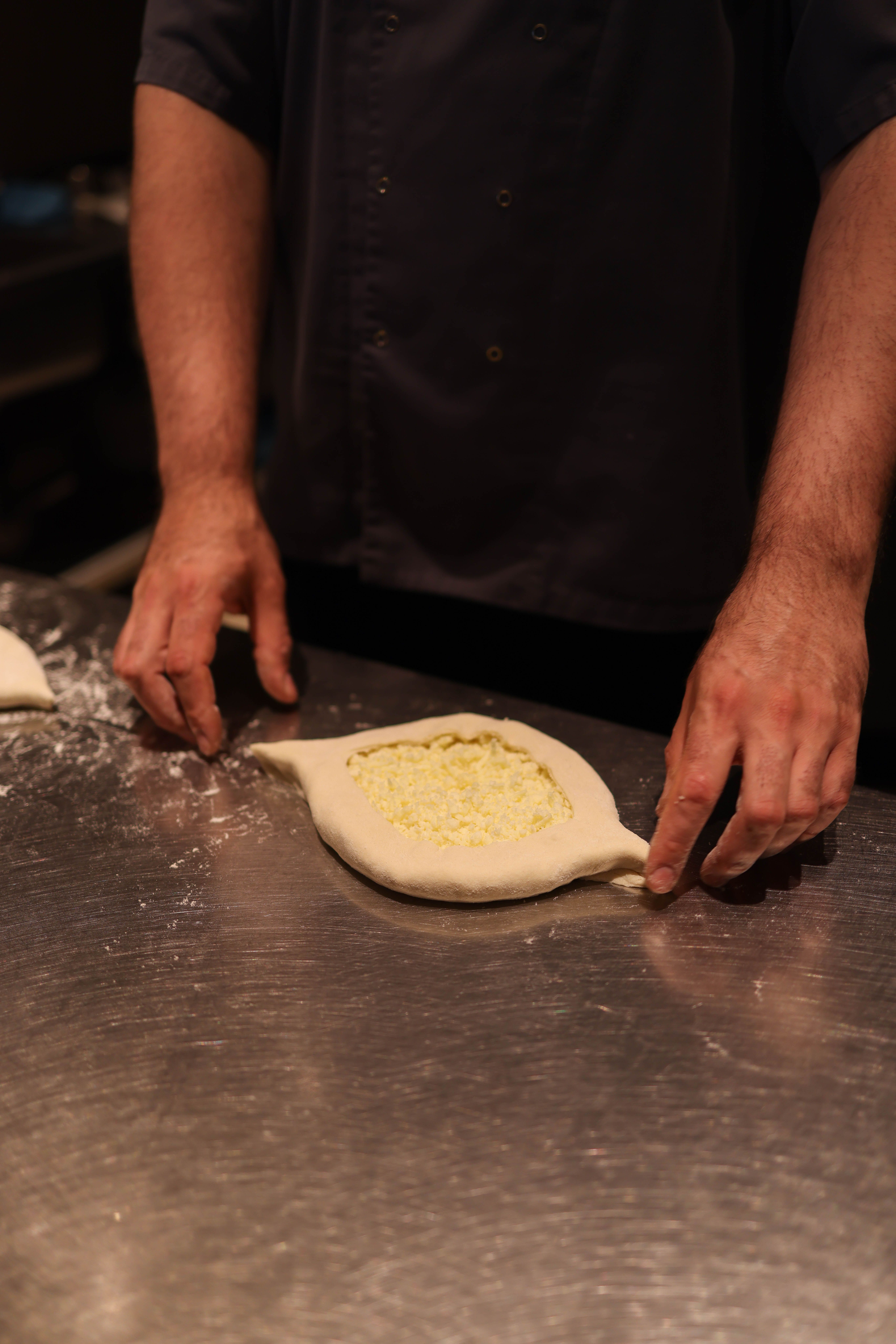 Chef working on authentic Georgian khachapuri in a restaurant kitchen setting.