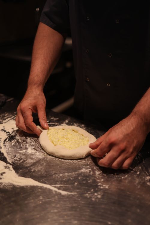 Free A chef skillfully shapes pizza dough indoors, focusing on culinary craftsmanship. Stock Photo