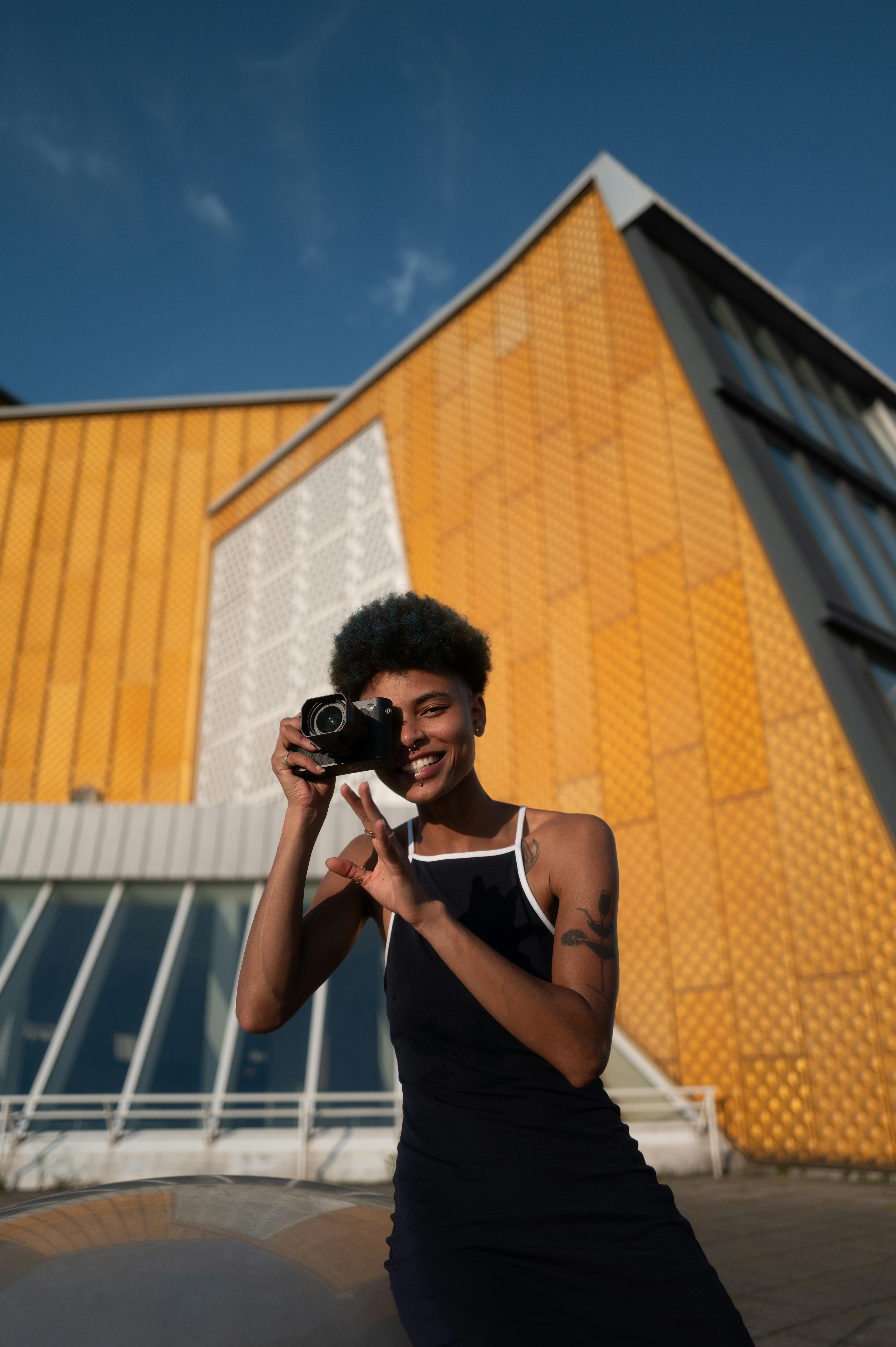 A joyful woman capturing moments with her camera in front of a modern building in Berlin.