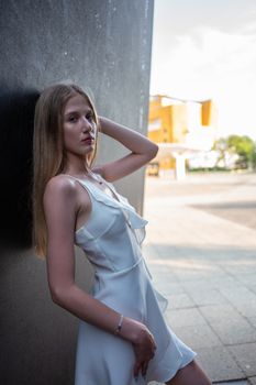 A fashionable young woman poses outdoors in a white dress in Berlin, Germany.