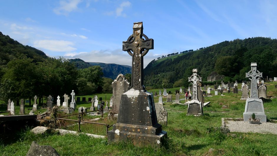 Fotomural Antiguo cementerio celta en Glendalough, Irlanda, con colinas verdes exuberantes y cruces de piedra.