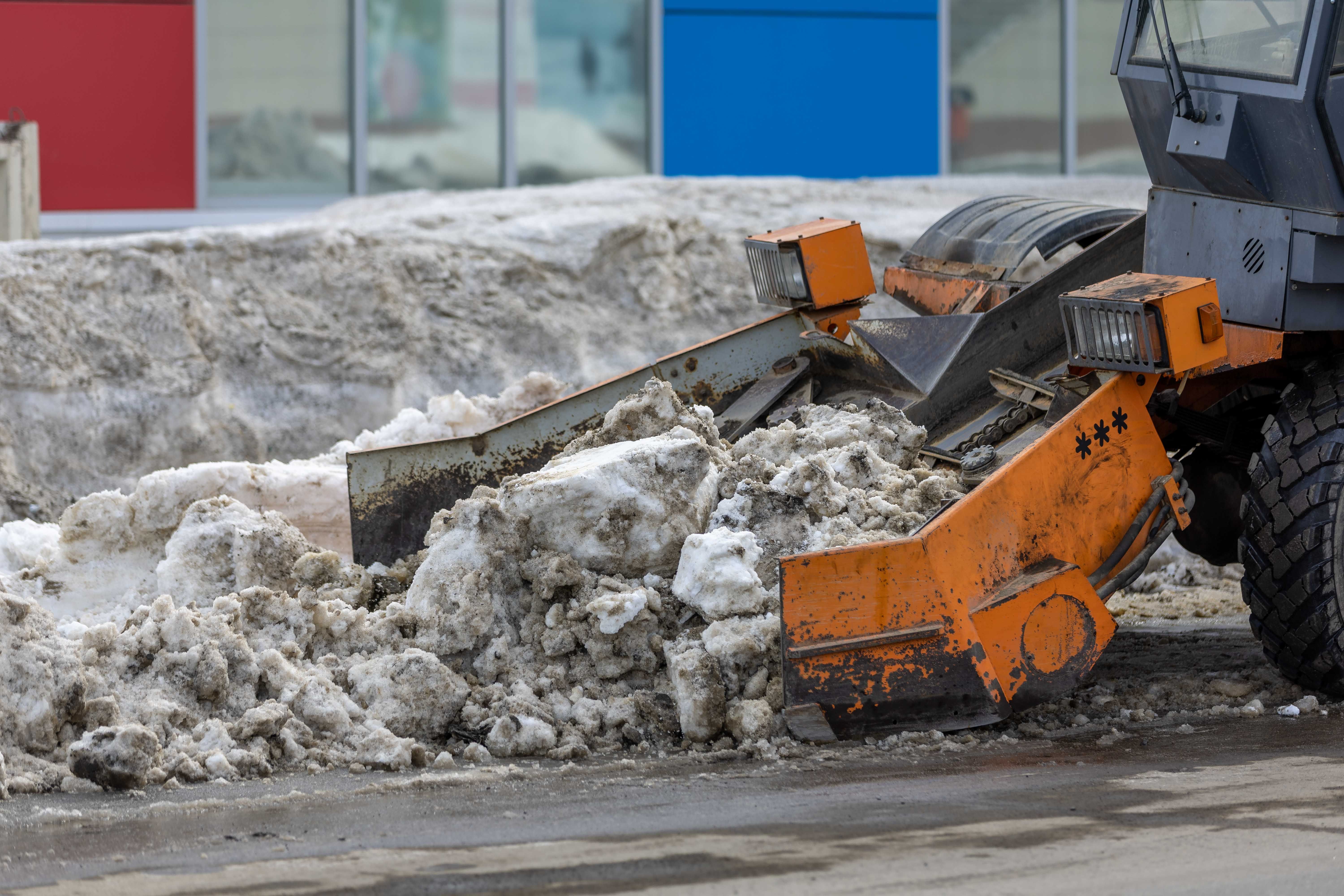 A commercial snow plow clearing a large parking lot during a heavy Stoneham snowstorm - snow plowing Stoneham MA