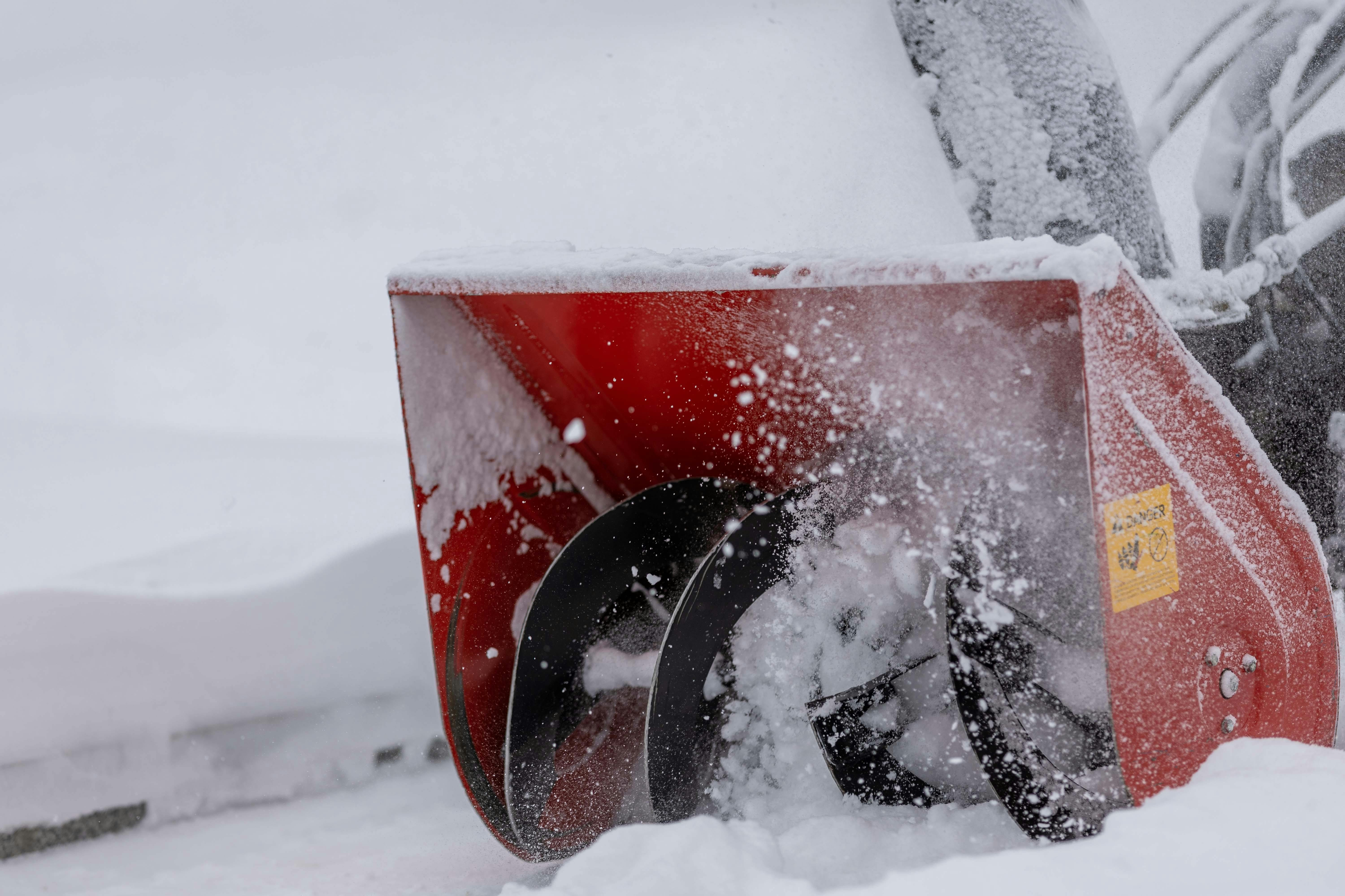 Powerful snowblower removing snow from a path during a winter snowstorm, showcasing action and efficiency.