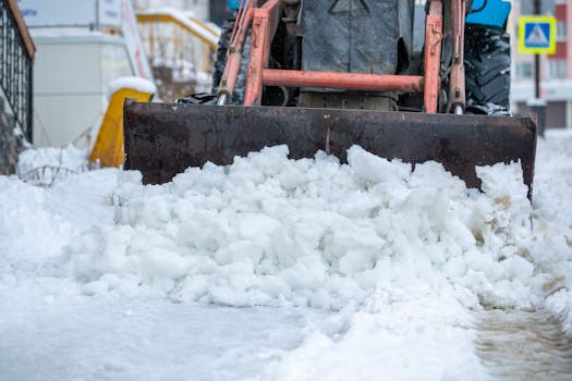 Snow plow clearing icy street after heavy winter snowstorm. Extreme cold weather conditions.