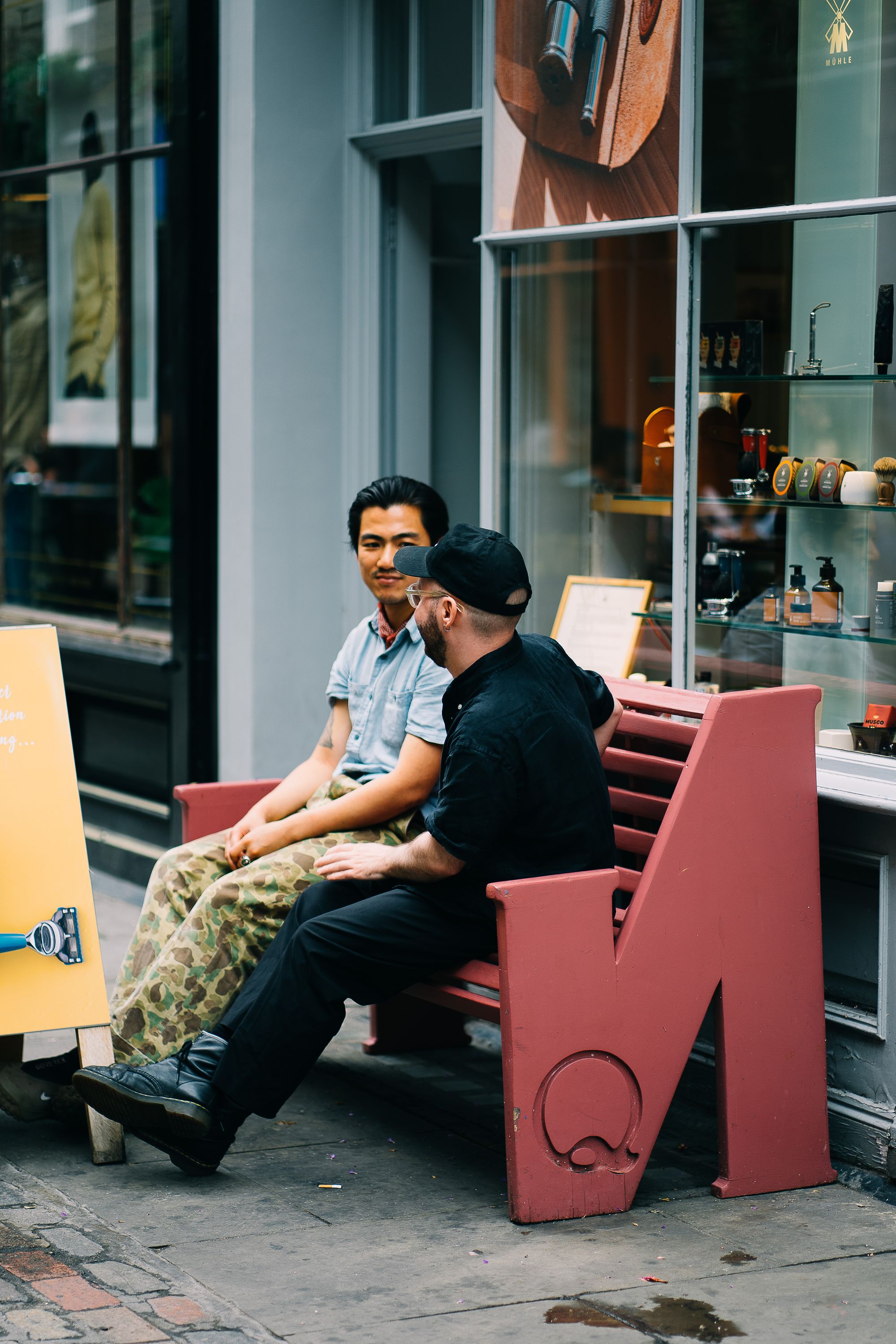 Two men sitting and talking outside a London shop photographed in daylight