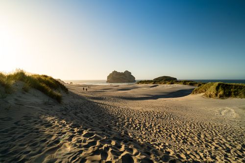 Free A sunny day at Wharariki Beach with sand dunes and distinct rock formations by the sea. Stock Photo