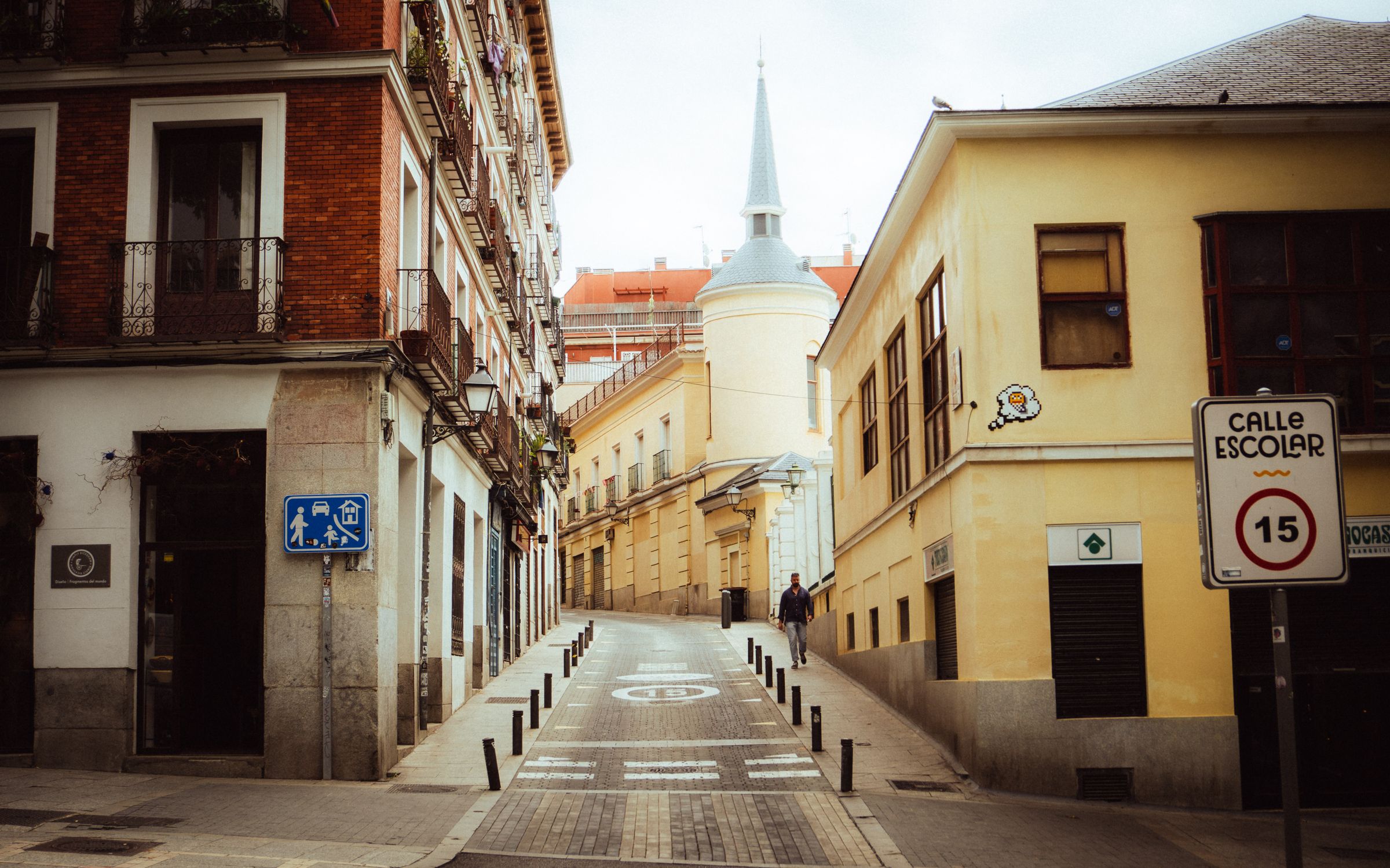 Charming narrow street with historic buildings in Madrid, Spain, under daylight.