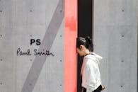 一名穿着白色连帽衫的女子走过保罗·史密斯商店的极简主义标志和墙壁