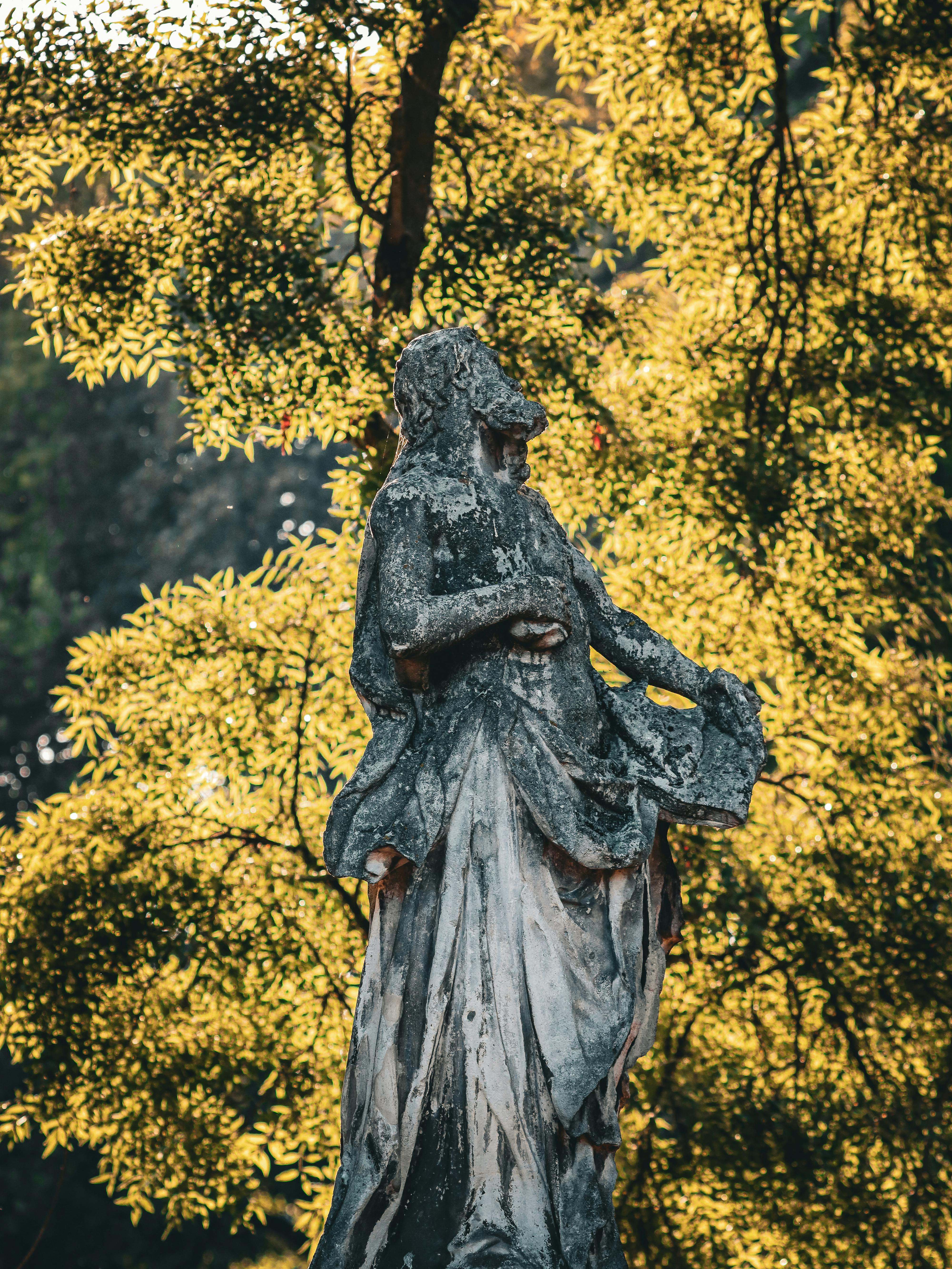 a statue of a woman in a park with trees