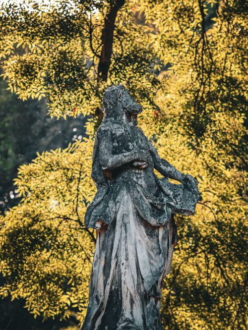 Free Beautiful stone statue amidst golden autumn leaves, capturing serene outdoor elegance. Stock Photo