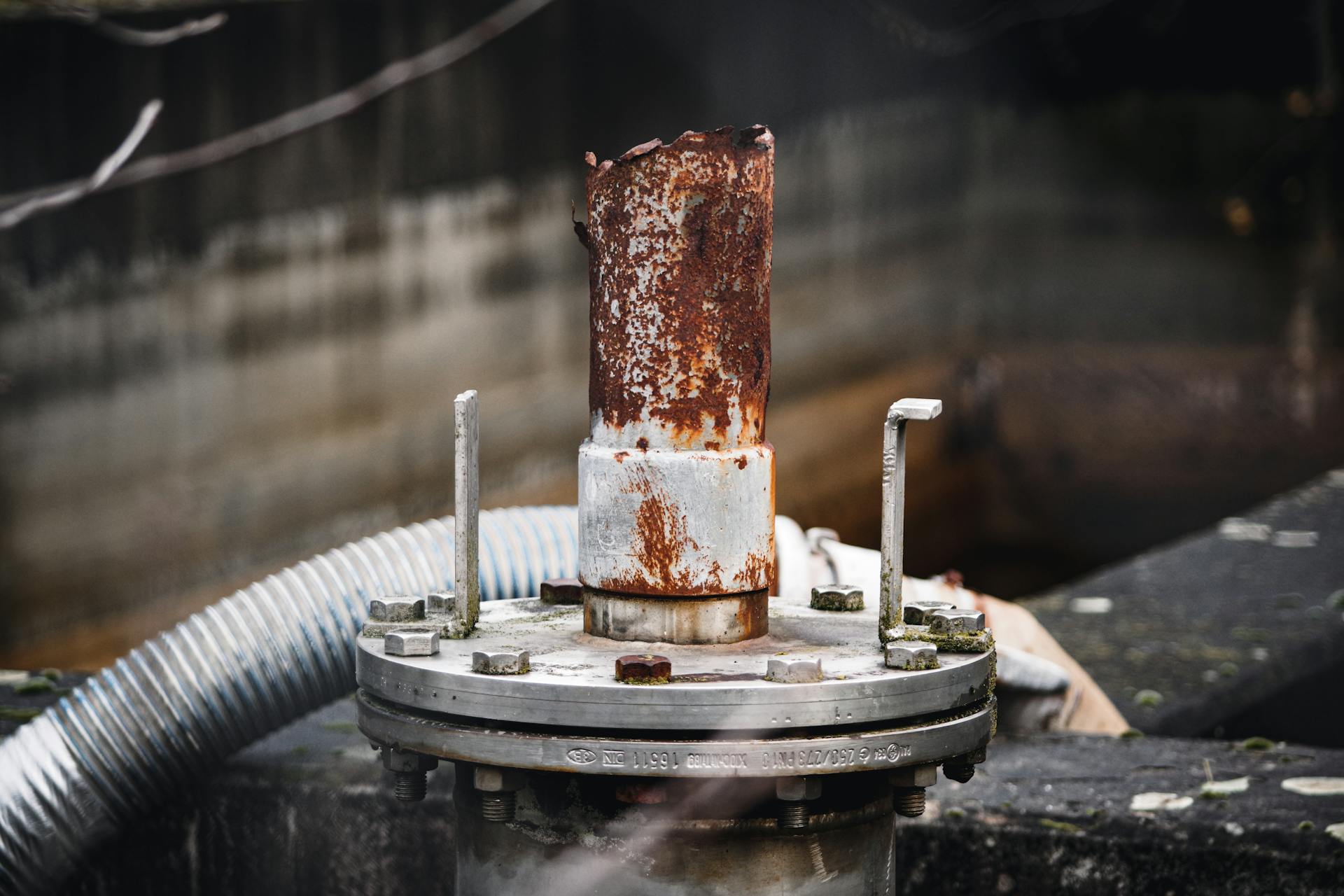 Close-up of a rusty industrial pipe with visible corrosion and decay.