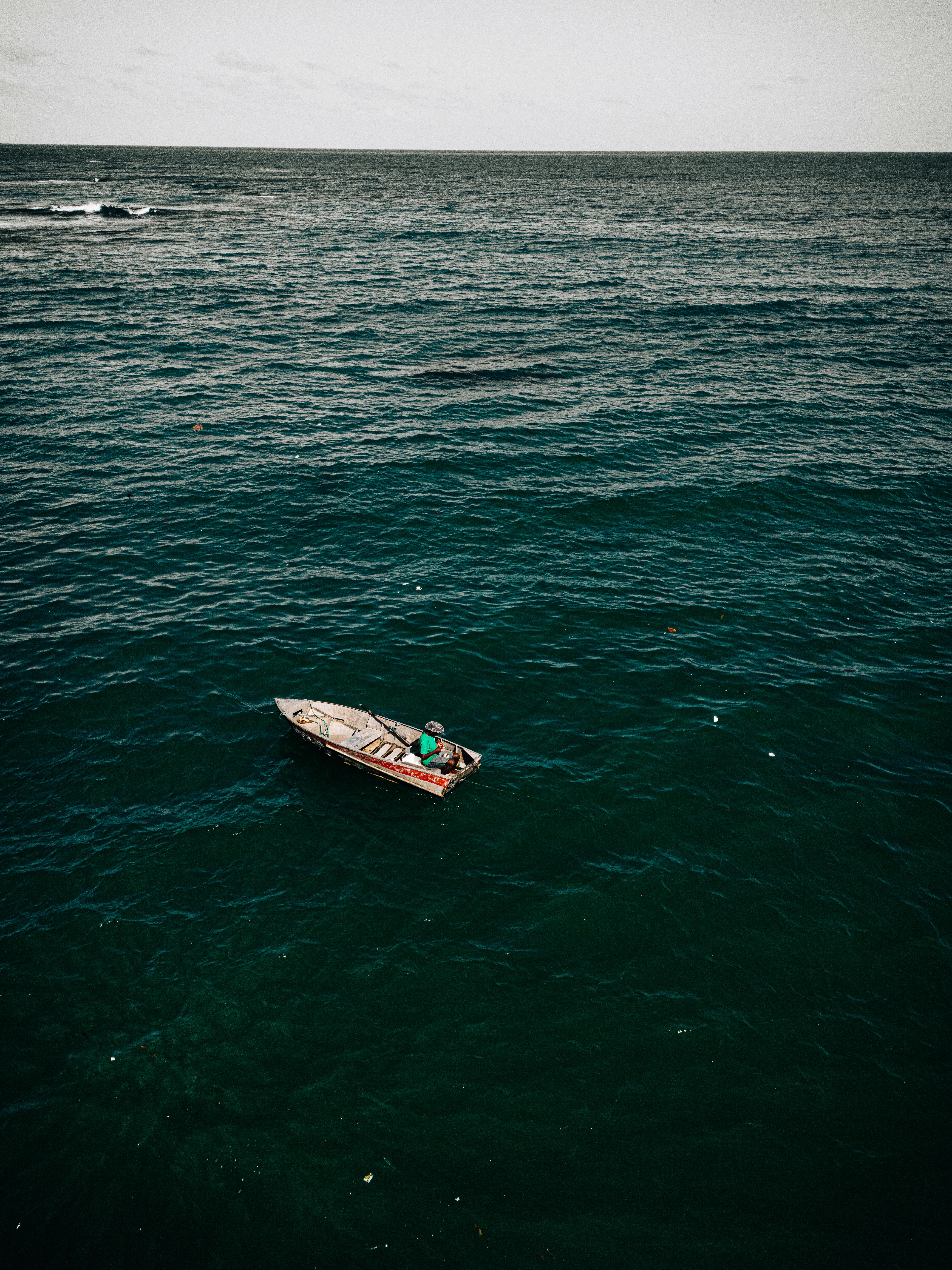 Aerial photo of a rowboat in an expansive ocean setting, showcasing tranquility and solitude.