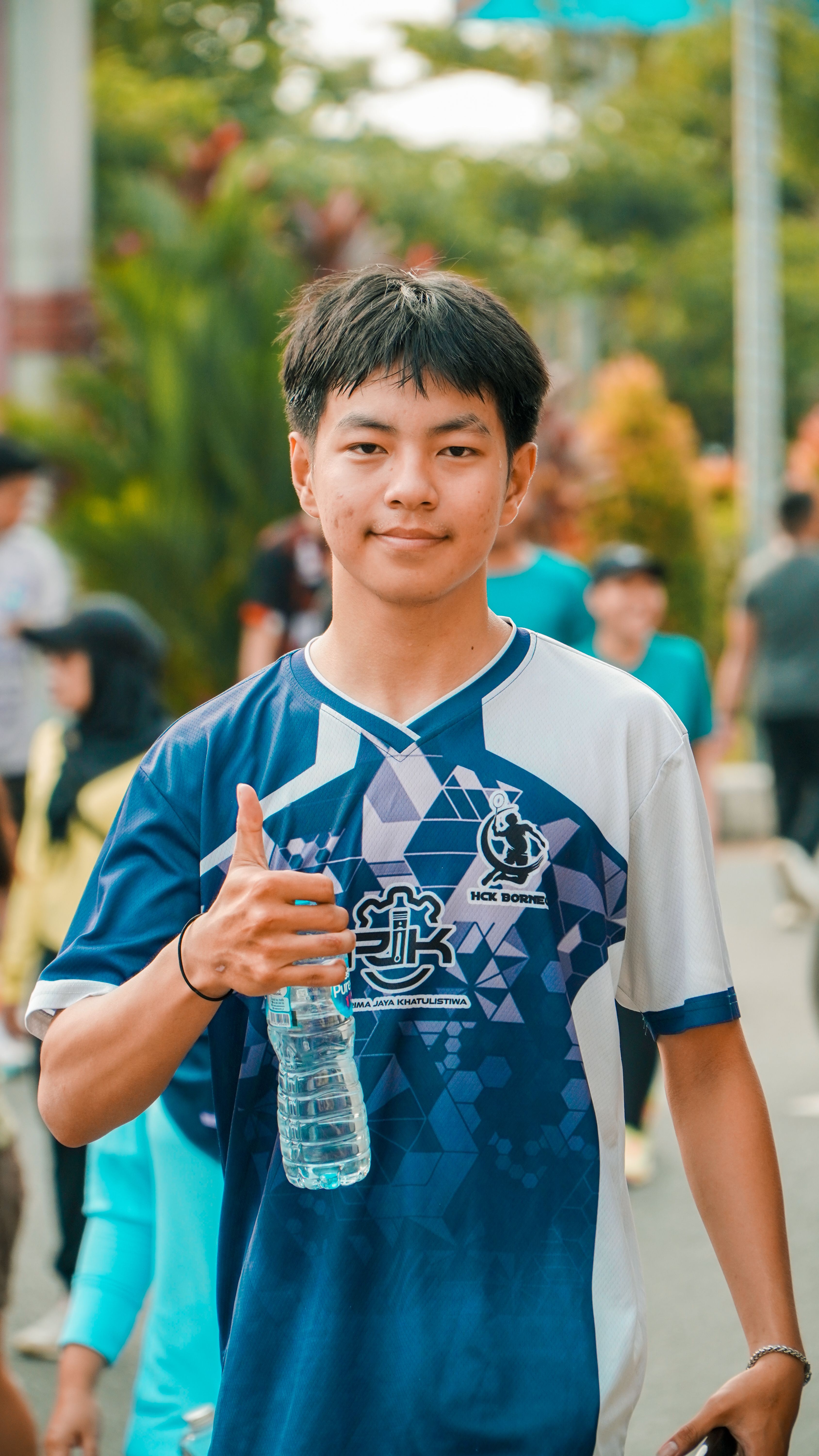Portrait of a young man smiling and giving a thumbs-up gesture at an outdoor street event in Pontianak, Indonesia.