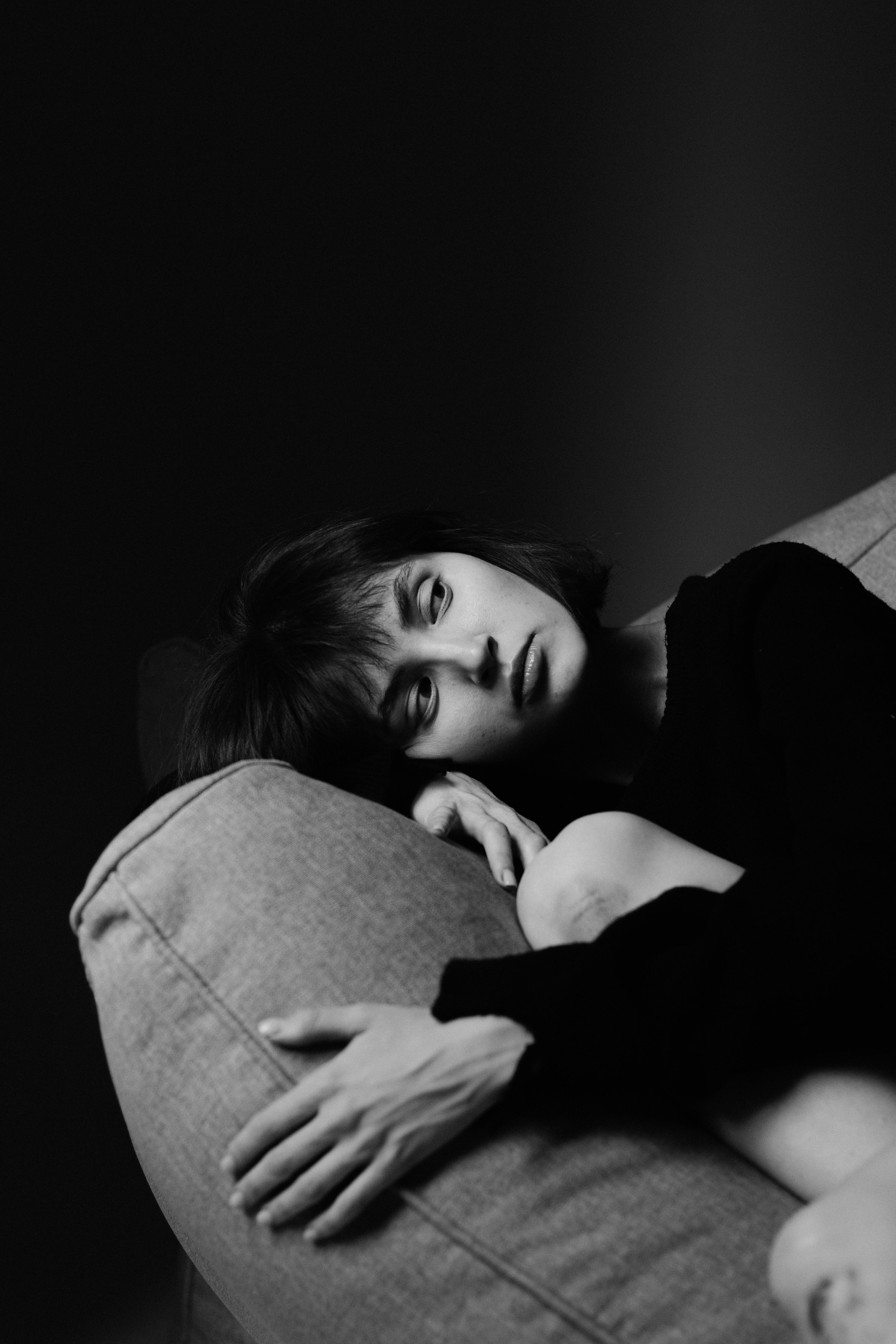 A woman sitting on a couch with her hand on her head · Free Stock Photo