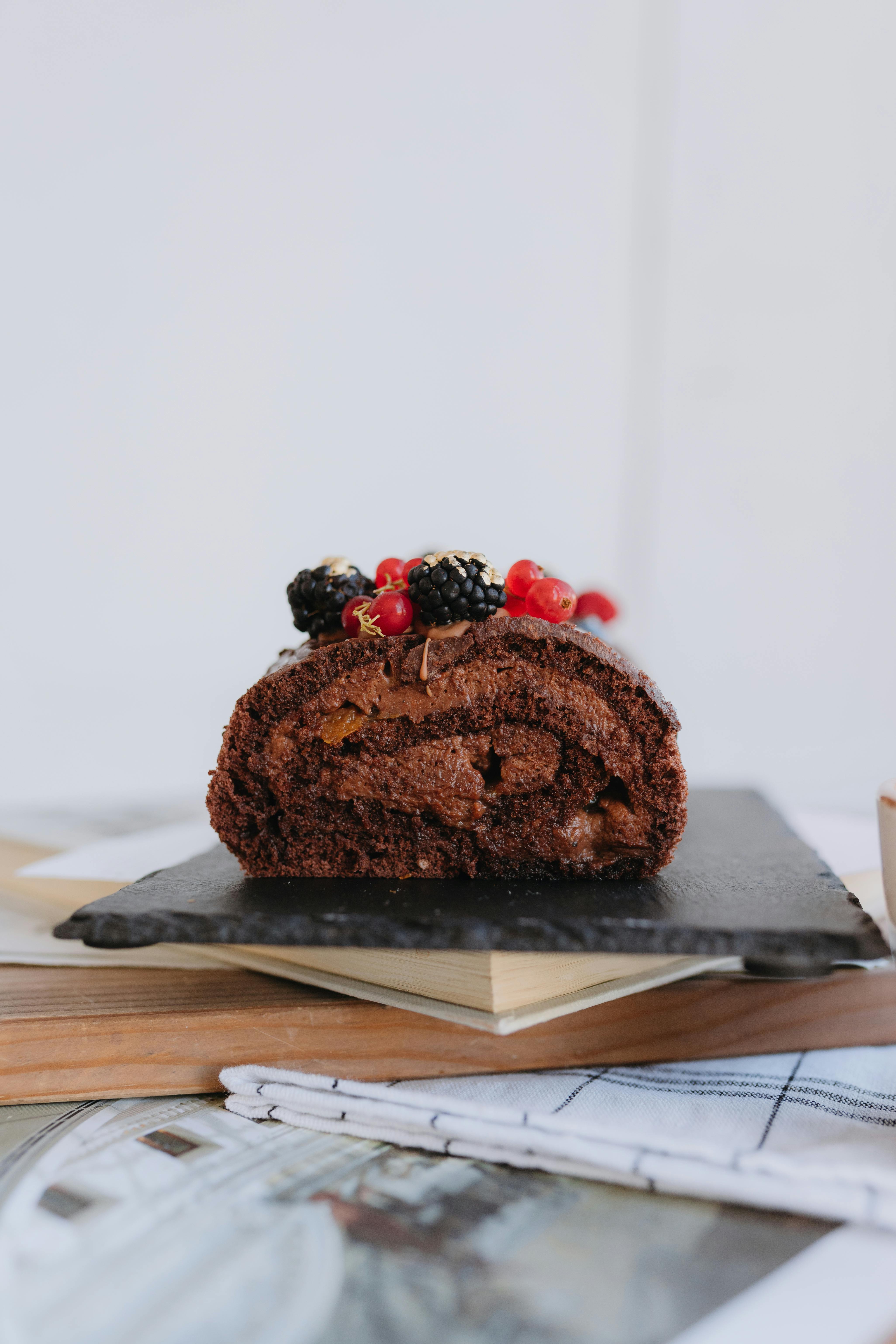 a chocolate cake with berries on top sits on a black plate