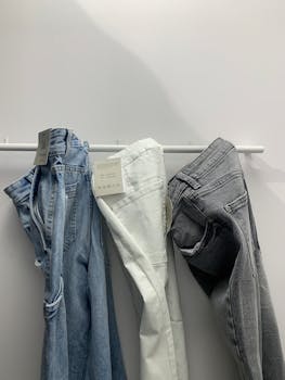 A stylish set of blue, white, and grey jeans hung in a minimalist retail display.
