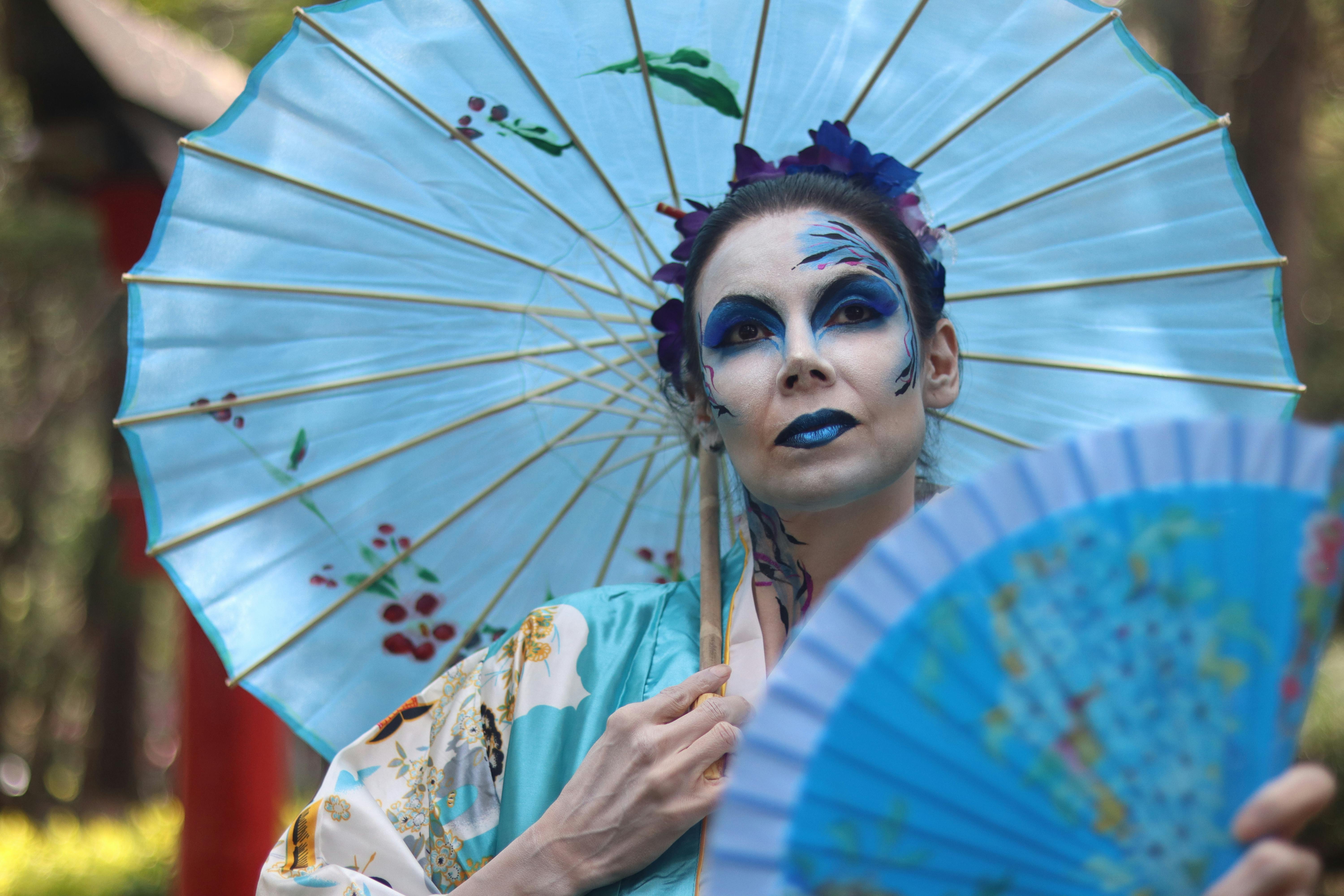 a woman with blue makeup and blue fan