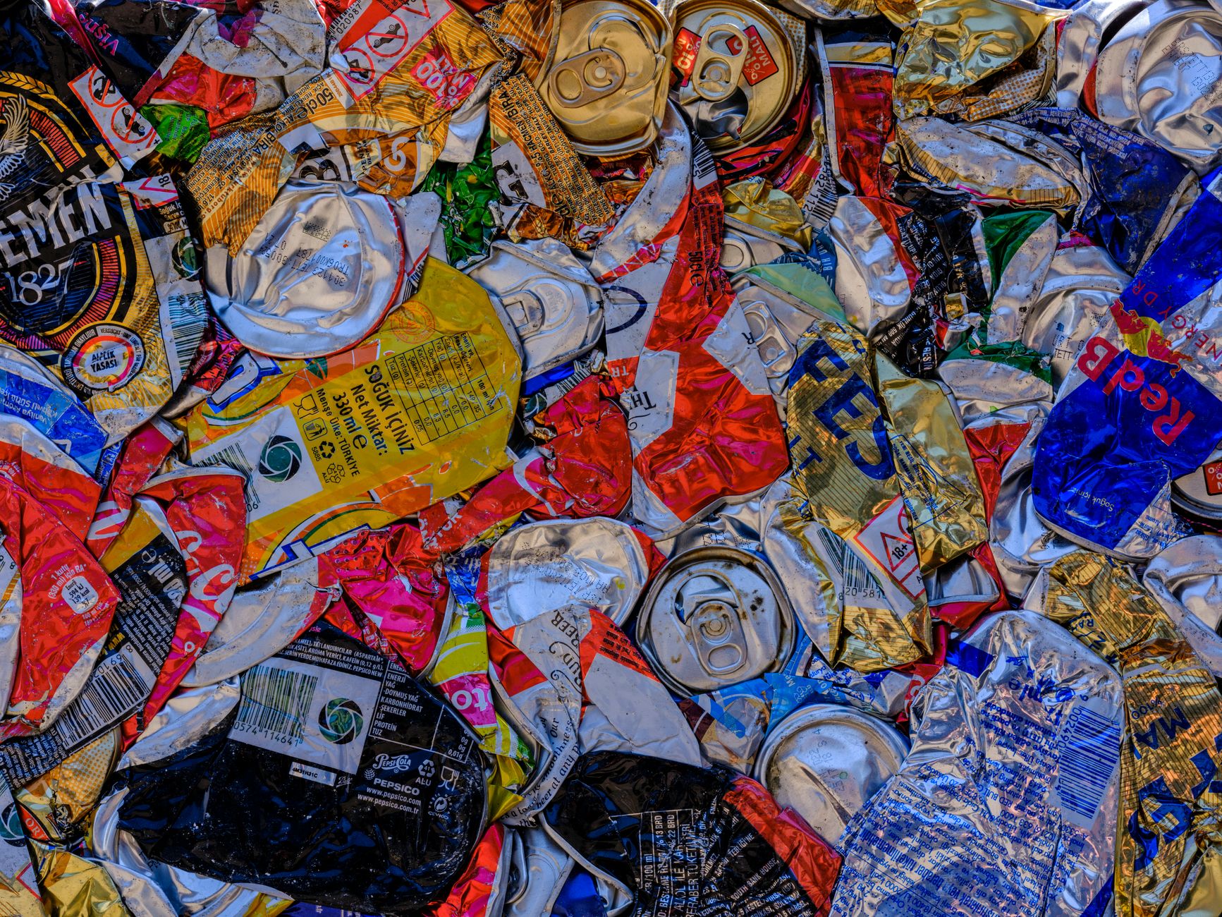 A vibrant display of crushed aluminum cans showcasing recycling art with a colorful pattern.