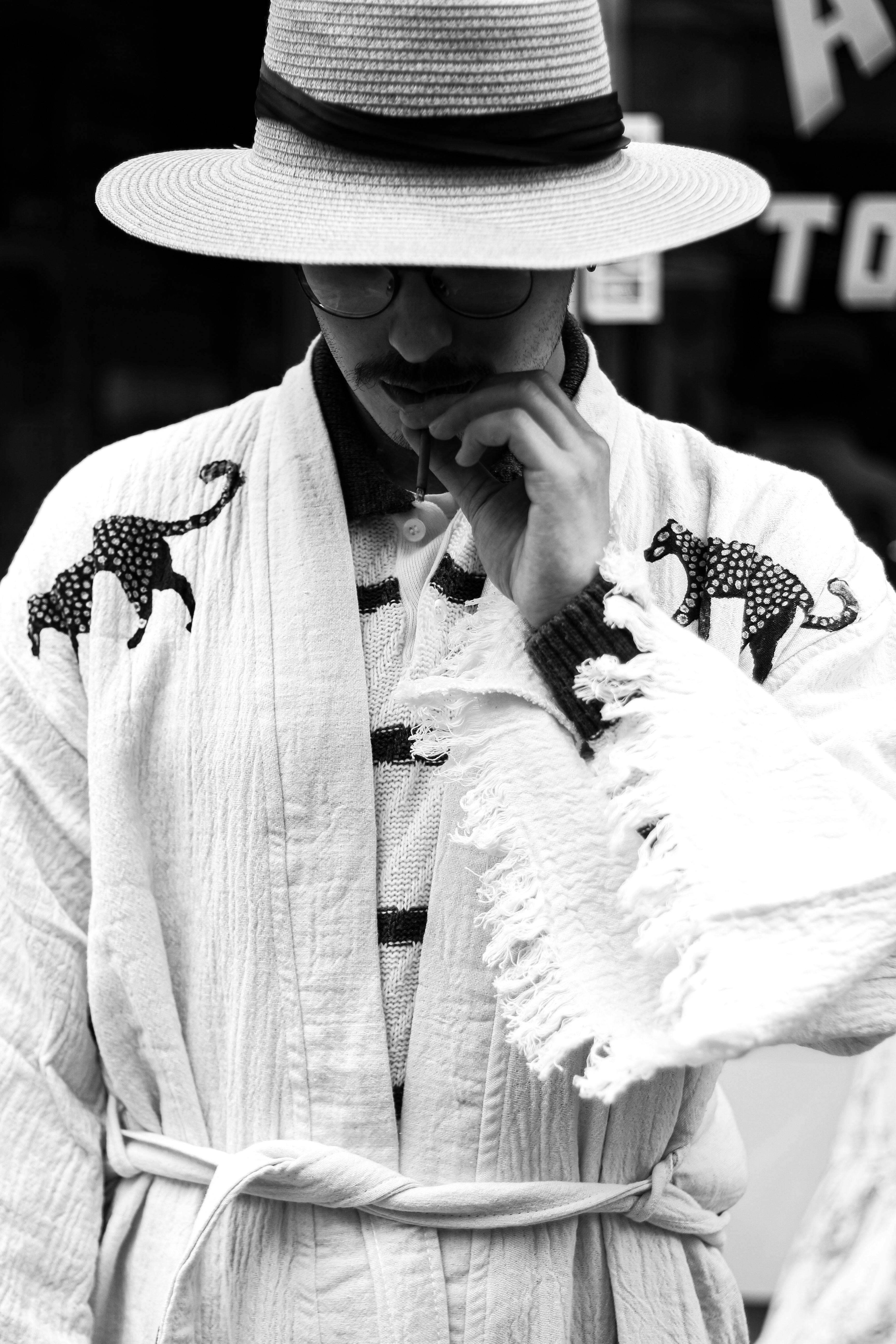 a man in a hat and robe is looking at his phone