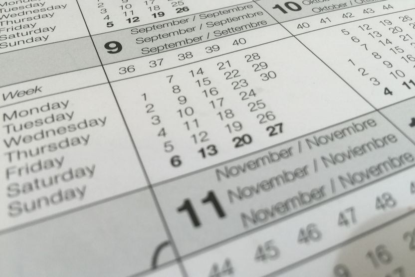 A close view of overlapping printed calendar pages showing week numbers, weekday names and month headings.