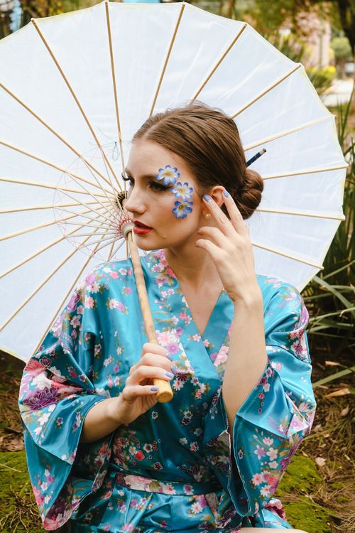 Free A stylish woman in a floral kimono holds a parasol in a serene outdoor setting. Stock Photo