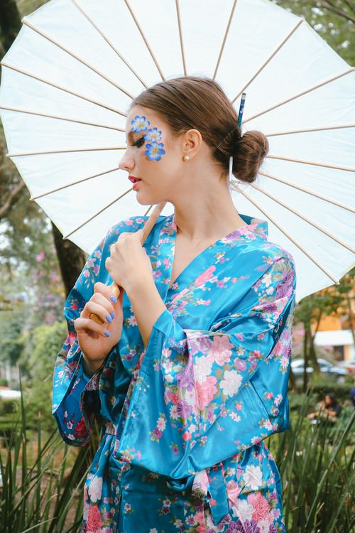 Free Young woman in colorful kimono and floral parasol enjoying a summer day outdoors. Stock Photo