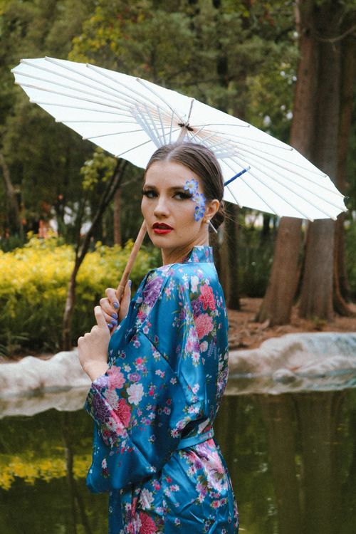 Free Woman in floral kimono holding a parasol in a serene outdoor setting. Stock Photo