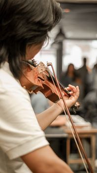Focused musician playing violin indoors during a concert setting, showcasing skill and artistry.