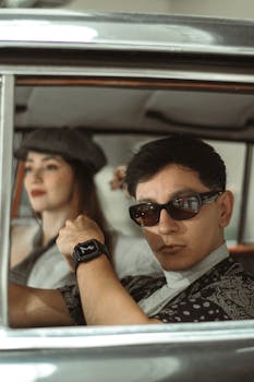 A fashionable couple seated in a classic vehicle showcasing retro style and modern accessories.