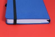 蓝色日记本上，黑色松紧带置于充满活力的红色表面